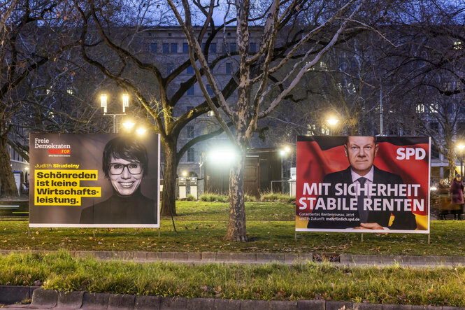 Zwei Wahlplakate stehen nebeneinander im öffentlichen Raum