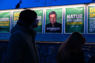 Menschen laufen an Wahlplakaten der Grünen vorbei, darunter auch eines mit dem Slogan :"Natur und Klima: Schützen!"