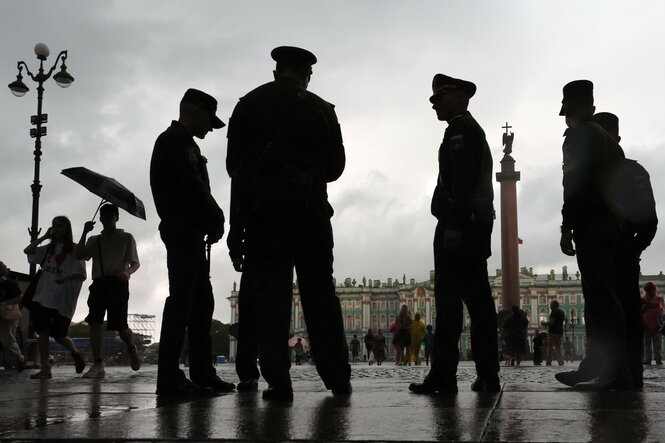 Eine gruppe von Männern in Uniform. Das Foto ist sehr grau, fast schon schwarz weiß. Das VBild ist von schräg unten aufgenommen, so dass die Männer noch bedrohlicher aussehen.