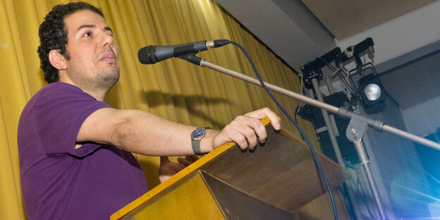 Hamed Abdel-Samad steht an einem Rednerpult vor einem Mikrofon.