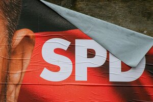 Ein Wahlplakat der SPD, das sich teilweise von Tafel löst