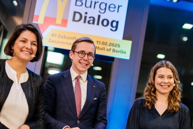 Drei Menschen lächeln in die Kamera in einer McDonald's-Filiale