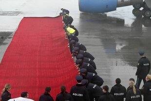 Polizei und Sicherheitspersonal rückt den roten Teppich zurecht in nasskaltem Wetter