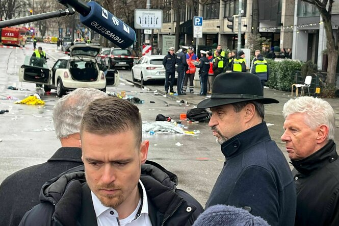 Bayerns Ministerpräsident Markus Söder und Dieter Reiter stehen vor dem abgesperrten Auto, das für die Tat benutzt wurde