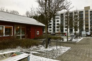 auf einem Holzhaus vor Hochhäusern liegt ein ewig Schnee