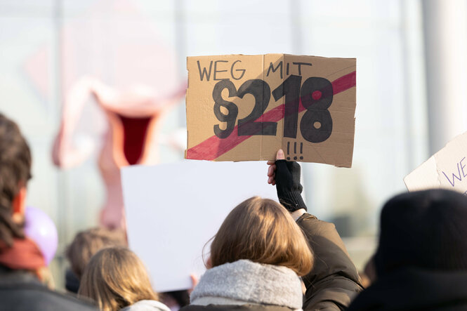 Protestaktion mit Schild fordert die Abschaffung des Paragraphen 218