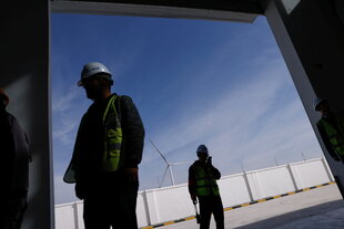 Arbeiter stehen im Schatten auf einer Baustelle für Windräder in China