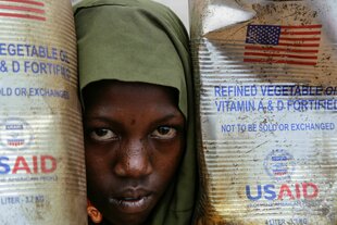 Ein Flüchtling in Afrika schaut zwischen zwei Behältern der US-Entwicklungsagentur USAID