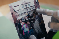 Ein behandschuhter Finger tippt auf ein Familienfoto