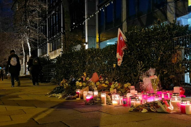 Kerzen, Blumen und eine Verdi-Fahne auf einem Bürgersteig