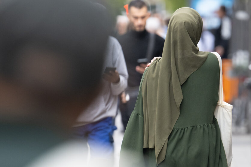 Eine Frau mit einem Kopftuch geht durch die Fußgängerzone von Offenbach.