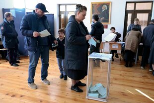 Menschen werfen Stimmzettel in eine Wahlurne