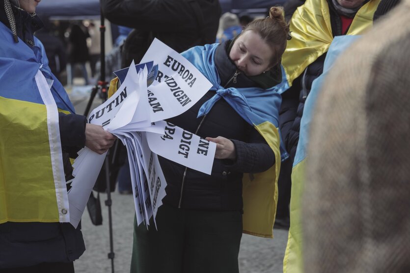 Menschen tragen bei Protesten die gelb-blauen Fahnen der Ukraine