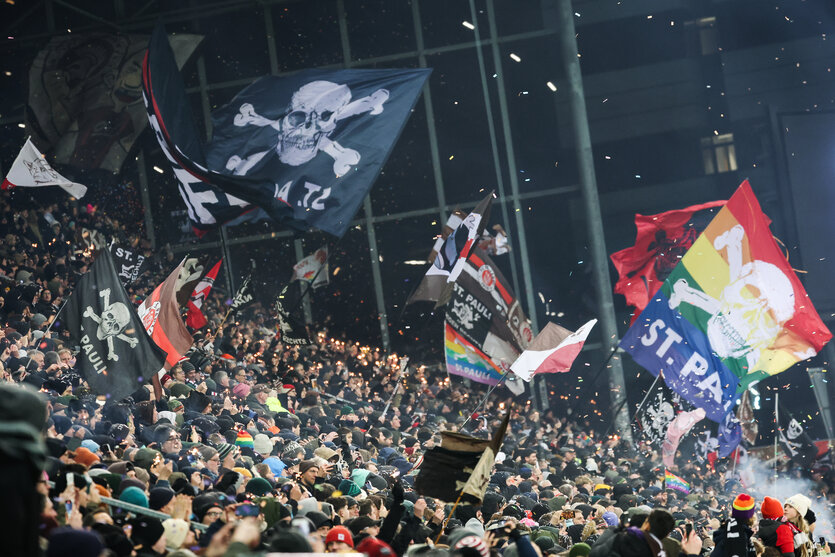 Fans im Stadion des FC St. Pauli auf der Tribüne schwenken Fahnen