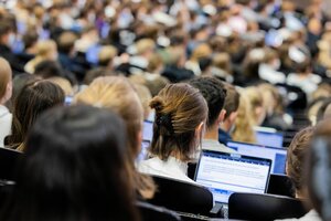 Studentinnen und Studenten sitzen während einer Vorlesung in einem vollen Hörsaal