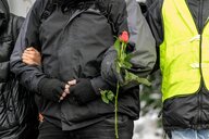 Nahaufnahme der Menschenkette: Zwei TeilnehmerInnen haken sich unter, eine Person hat eine Rose in derHand - die Gesichter sind abgeschnitten