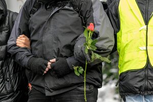 Nahaufnahme der Menschenkette: Zwei TeilnehmerInnen haken sich unter, eine Person hat eine Rose in derHand - die Gesichter sind abgeschnitten