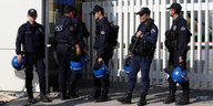 Fünf türkische Polizisten in schwerer Uniform stehen vor einem weißen Zaun