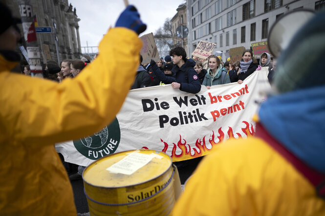 Demonstranten der Fridays For Future Bewegung mit Transparent Die Welt brennt Politik pennt