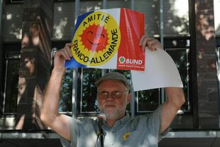 Axel Mayer bei einer Demonstration: Er hält eine Schild hoch mit der Aufschrift: Amitie Franco-Allemande