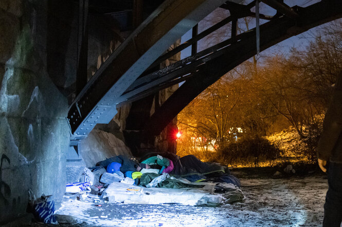 Mensch in Schlafsäcken unter einer Brücke in Hamburg.