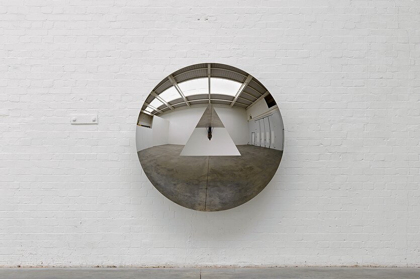 Die aus mehreren Spiegeln bestehende Installation „Concave Convex Mirror (Triangle)“ des indisch-britischen Bildhauers Anish Kapoor hängt an einer weißen Wand.