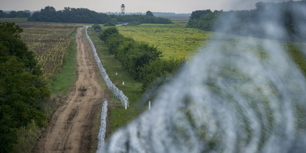 Ein Zaun aus Stacheldraht schlängelt sich durch die ungarische Landschaft
