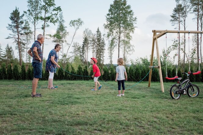 Großeltern und Enkel spielen auf einer grünen Wiese