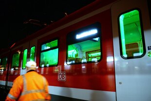 Ein Arbeiter in geht an einer beleuchteten S-Bahn vorbei