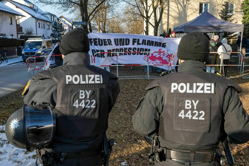 Zwei Polizisten stehen vor einer kleinen Protestaktion für Hanna S. Auf dem Transparent, das hinter einer Absperrung hochgehalten wird, steht: Feuer und Flamme der Repression