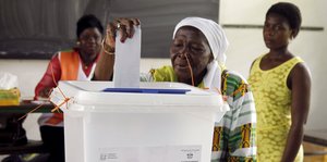 Frau wirft Wahlzettel in Urne ein
