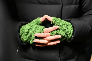 Die Hände von Annalena Baerbock , sie trägt grüne Wollhandschuhe ohne Finger und eine schwarze Jacke