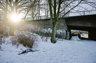 Eine Brücke im Schnee, darunter ein kleines Zelt