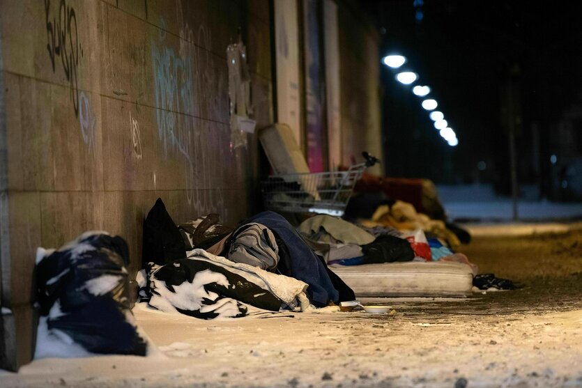 Obdachlose Menschen schlafen im Schnee unter einer Brücke