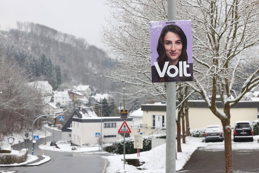 Ein Wahlplakat der Partei "Volt" in einer verschneiten Stadt