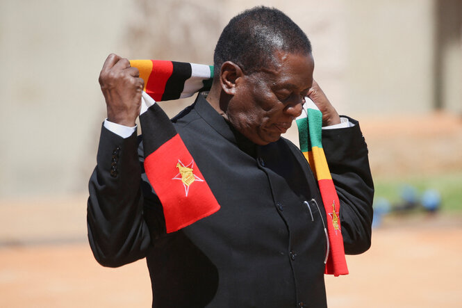 Emmerson Mnangagwa blickt im laufen auf den Boden während er einen Schal in den Farben der Afrikanischen Union um seinen Hals legt