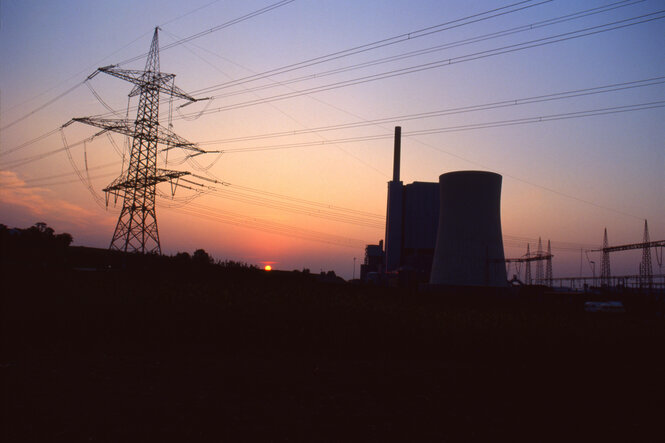 Sonnenuntergang, in der Silhouette ist ein Strommast und Kraftwerkskühlturm sichtbar