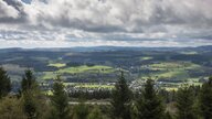 Blick über Bäume auf sauerländische Landschaft unter Wolken