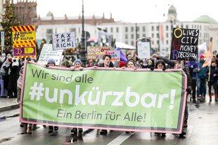 Demonstrierende laufen mit einem Banner mit der Aufschrift #unkürzbar.