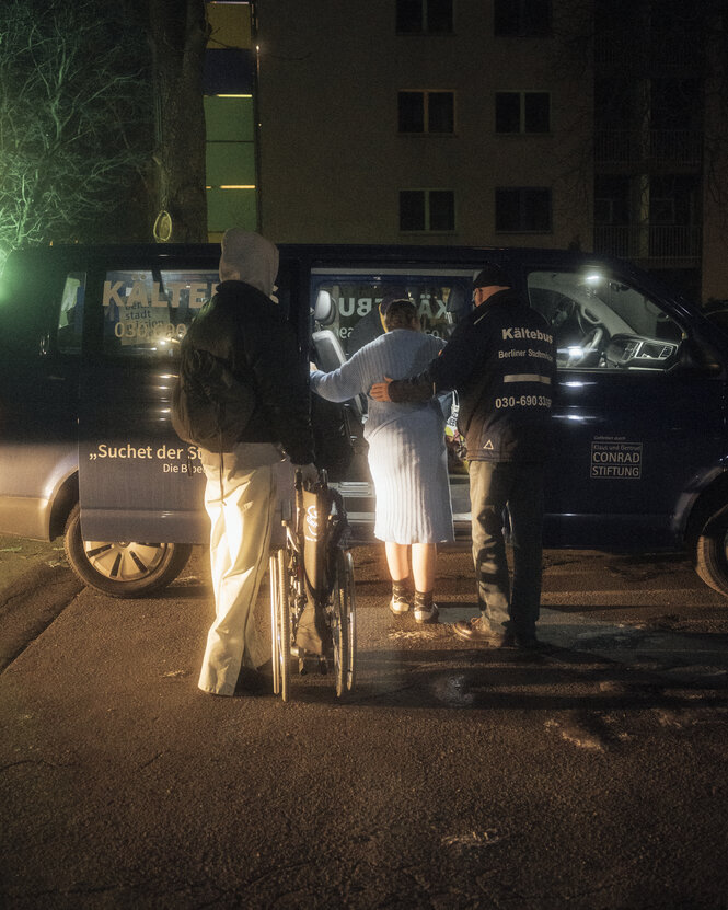 Eine Person hilft einer anderen beim Einstieg in den Bus, eine andere Person hält einen Rollstuhl