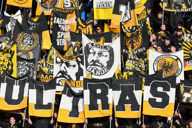 Ultras von Alemannia Aachen die Embleme der Fangruppierung Karlsbande hochhalten