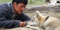Shaofeng Feng als Chen Zhen spielt in einer Szene des Kinofilms „Der letzte Wolf“ mit einem Wolf.