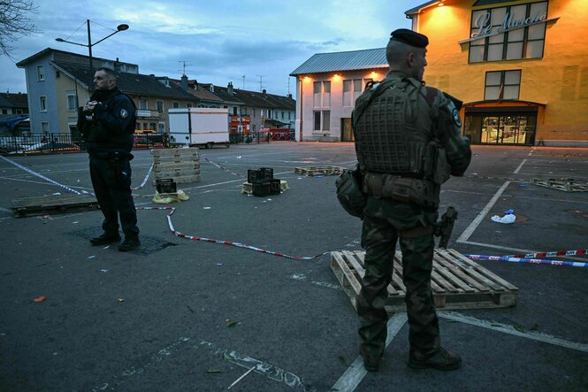 Ein Polizist und ein Soldat stehen am Ort eines Messerangriffs