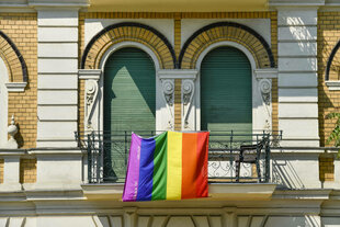 Eine Regenbogenflagge hängt an einem Balkon