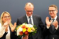 Friedrich Merz bei einer Pressekonferenz mit Blumenstrauß