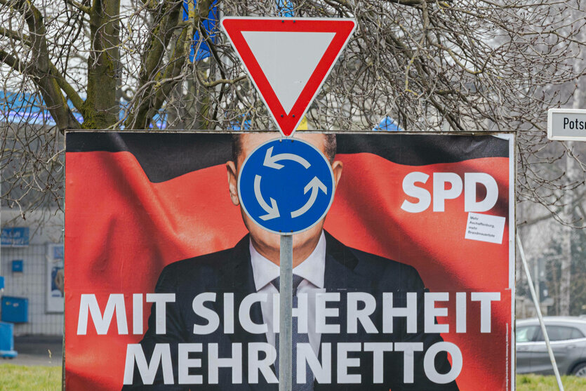 Ein Verkehrsschild vor einem Wahlplakat von Olaf Scholz.