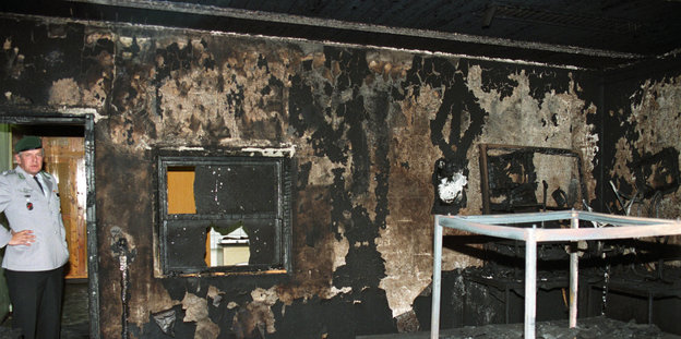 Ein offizier steht an der Tür einer ausgebrannten Kantine.