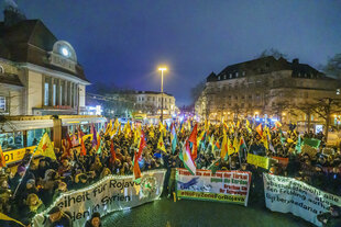 Demonstrationsteilnehmer stehen mit Bannern vor dem Südbahnhof in Frankfurt am Main.