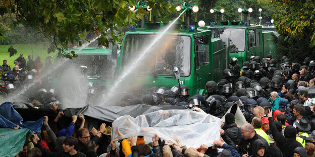 Ein Wasserwerfer spritzt im Schlossgarten in Stuttgart auf Demonstranten.