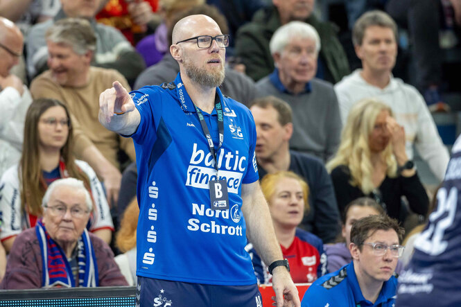 Ales Pajovic steht vor einer Zuschauertribüne macht Handzeichen beim Spiel von Flensburg-Handewitt gegen Melsungen.